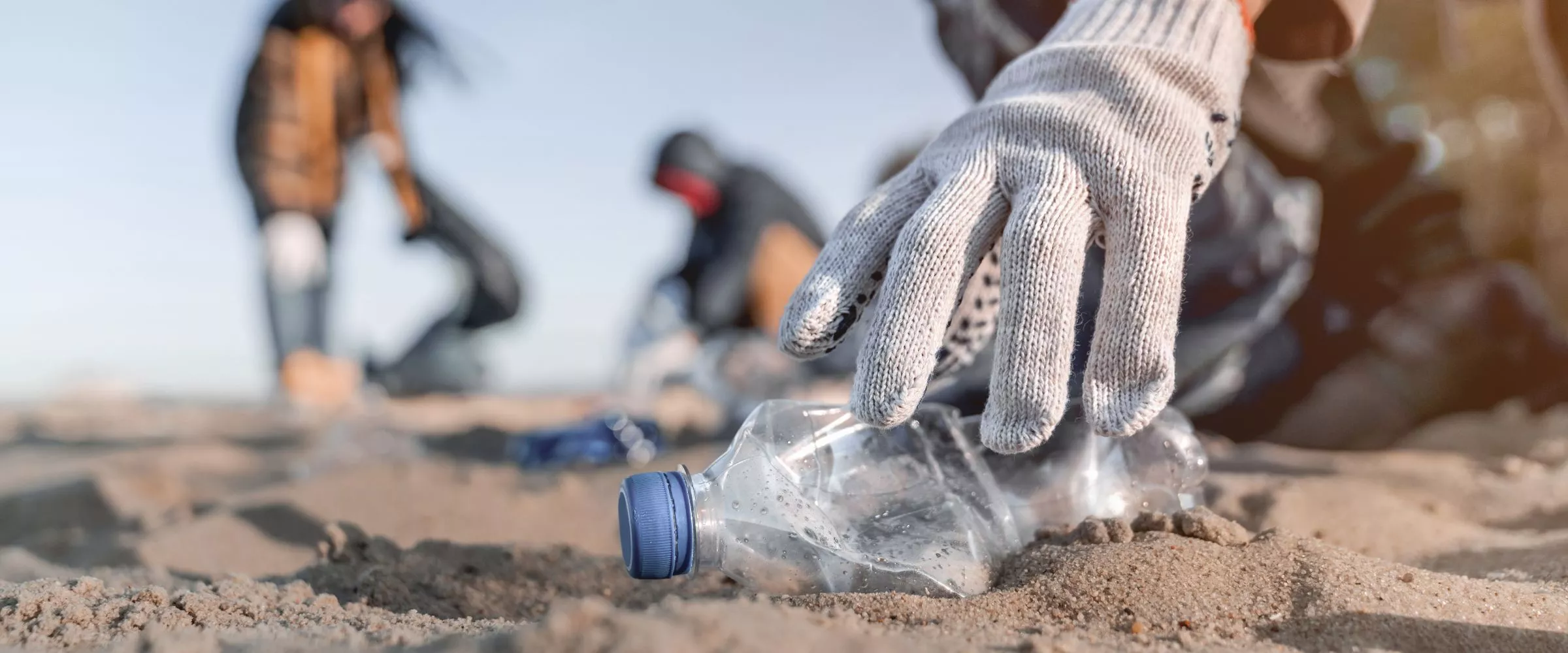 man picking scrap plastic bottles on beach